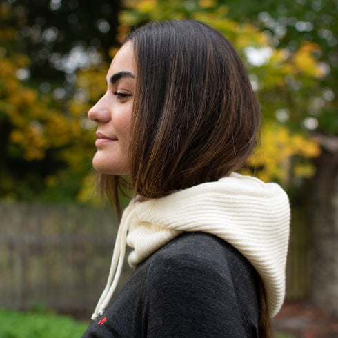 Dame mit einem Merino Kapuzenschal in der Farbe ecru und einem anthrazit Langarmshirt.